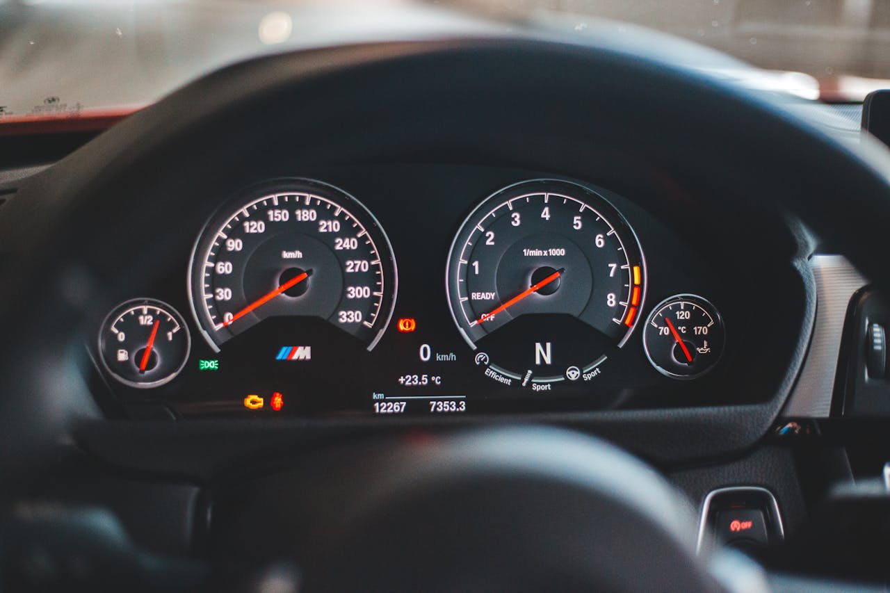 why-choose-us Close-up of a luxury car dashboard display with illuminated gauges and speedometer.